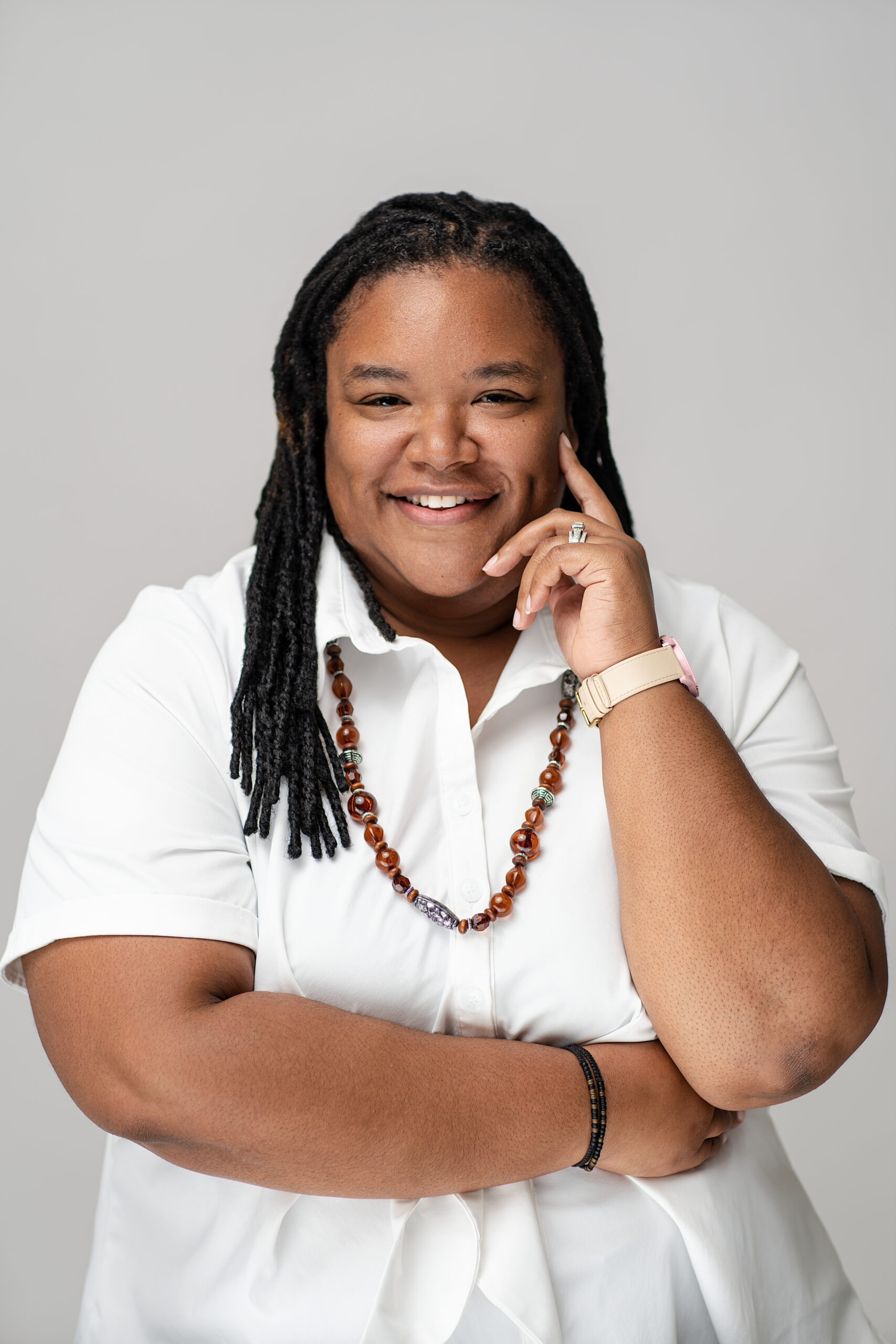Dr. Jurdene Coleman with left hand on cheek, right arm across body smiling